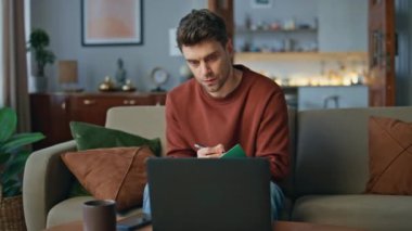 Ev kanepede dizüstü bilgisayarlı web kamerasıyla uzaktan çalışan bir çalışan toplantısı. Gerçekten yakışıklı bir öğrenci, deftere uzaktan ders çalışıyor. Akıllı serbest çalışanın iş yazma sorunuyla ilgili video çağrısı var