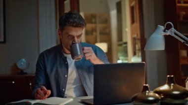 Düşünceli acemi, gece yarısı ev ofisinde çay içiyor. Elinde kalem tutan serbest çalışan adam bilgisayarın önünde oturuyor. Meşgul ciddi adam içecekten zevk alıyor. Karanlık evde notlar yazıyor. 