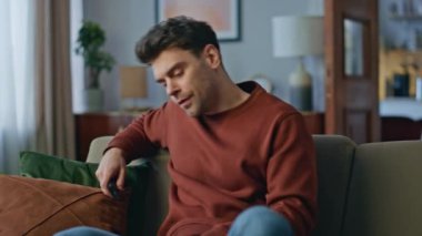 Yorgun bir adam zor bir günün ardından kanalı gevşetiyor. Kanepede uzaktan kumandayla televizyon programını değiştiren sıkıcı yakışıklı adam. Dinlenen hipster televizyon seyrediyor oturma odasında.