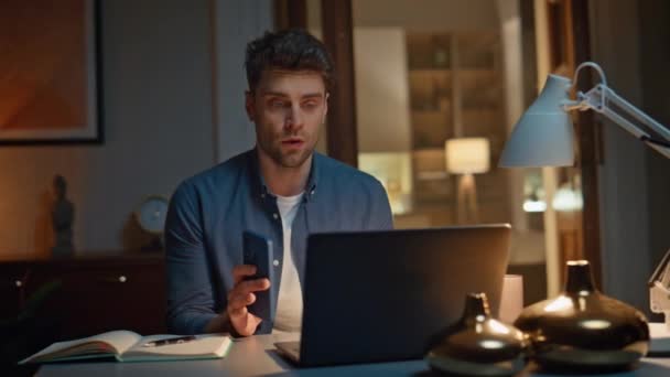 真面目な男は夜の閉鎖でコンピュータの座席テーブルでウェブカムチャットを話します 自宅でラップトップビデオ通話で仕事を議論するハンサムなビジネスマン オンラインカンファレンスの遅れビジネスを持っている自信のある男 — ストック動画