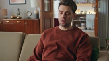 Yorgun bir adam kanepe dairesinde oturur ve akıllı telefon ekranını kapatır. Zor bir iş gününden sonra cep telefonundan mesaj okuyan yorgun ve çekici bir adam. Yorgun erkek rahat bir kanepede telefonuyla dinleniyor..