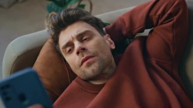 Düşünceli adam kanepede uzanıp dinleniyor. Gün sonunda kapanıyor. Cep telefonu ekranına bakan gergin bir adam dairedeki kötü haberlerden endişeleniyor. Kanepede cep telefonuyla düşünen çok çalışan erkek..
