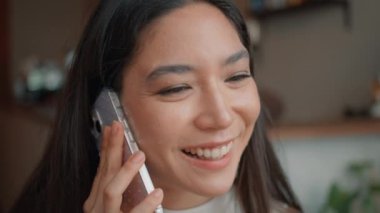 Kahvehanede cep telefonuyla konuşan gülümseyen bir genç. Akıllı telefonu arayan Asyalı çekici bir kadının portresi. İyi sohbetler. Neşeli Taylandlı kızın kafede telefonla dostça bir iletişimi var.