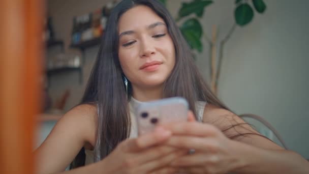 Menina Despreocupada Mensagens Smartphone Aconchegante Cafetaria Perto Relaxado Asiático Morena — Vídeo de Stock