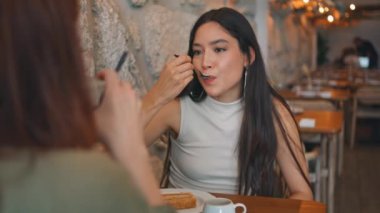 Asyalı kız, kafeteryada arkadaşıyla lezzetli bir tatlı yemeğinin tadını çıkarıyor. Pasta yiyen çekici esmer, tanınmayan bir arkadaşla konuşuyor. İki kız arkadaş hafta sonunu rahat bir kafede geçiriyorlar..