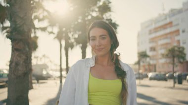 Palmiye ağaçlarının arka sokaktaki portresine gülümseyen bir model poz veriyor. Mutlu gezgin kız, güneş ışınlarıyla neşe içinde doğayı yakından izliyor. Tropikal ortamda rahatlayan güzel bir kadın. Hafta sonu etkinlik kavramı