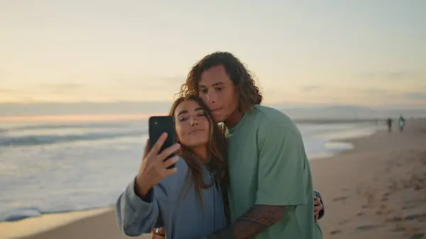 快乐的青少年在日落海滩特写时自拍 快乐的情人们 在晚上的海上自然中 用手机自拍拥抱 迷恋的年轻人在海滨温柔地亲吻着女人 — 图库照片