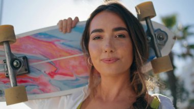 Şehrin portresinde kaykay tutan havalı genç bir bayan. Hippi kadın, tropikal ara sokakta poz veriyor. Aktif patenci kız uzun kaykaya binmeye hazır. Ekstrem spor konsepti