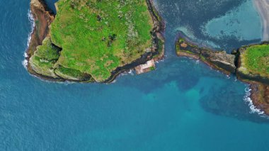 Havadan okyanus uçurumları kıyı şeridi manzarası. Sakin bir yaz gününde turkuaz okyanus sakin deniz kıyılarını yıkıyor. Kayalık sahil kıyısı olan yeşil sahil kıyılarının nefes kesici insansız hava aracı görüntüleri. Vahşi terk edilmiş manzara konsepti