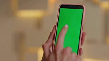 Smartphone kullanıcısı iş yerinde görüntüye dokunuyor. Tanımlanamayan iş kadını şirket ofisinde yeşil ekranlı cep telefonunu dinliyor. Kadın elleri krom anahtarlı cep telefonu tarama uygulaması.