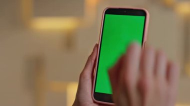 Modern ofisteki yeşil ekranlı akıllı telefonda internette sörf yapan tanınmayan bir kadın. Kadın elleri kroma tuşlu cep telefonunu kaydırıyor. Bilinmeyen iş kadını cep telefonundan mesaj okuyor.