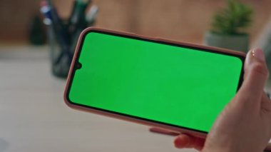 Tanımlanamayan bir kadın şirket ofisinde otururken akıllı telefon kullanıyor. Kadın elleri yatay krom anahtar cep telefonunu tutuyor. İnternet sosyal ağlarını izleyen bilinmeyen bir kız görüntülere göz atıyor.