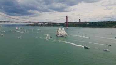 Kasvetli hava manzarasında turist yatları nehir kıyısında yüzüyor. Lisboa şehri bulutların altında ünlü gezginlerle doludur. Deniz koyunun yaz manzarasında yüzen tekneler. Tatil ve turizm konsepti