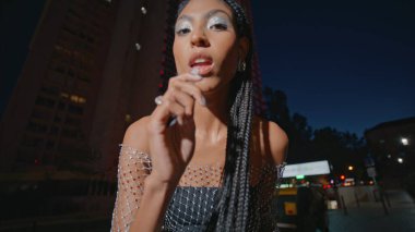 Gece lambası sokak resmine ruj sürmüş. Kahverengi tenli, modaya uygun bayan makyajını düzeltiyor. Şehir Bulvarı 'na yakından bakıyor. Modern kadın Avenue 'da kameraya bakıyor.