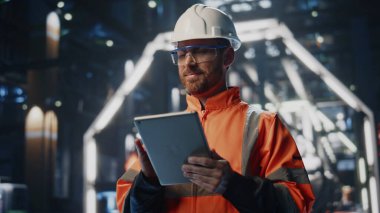 Gülümseyen mühendis bilgisayarı yakın çekim ile denetim yapım atölyesi yapıyor. Miğfer üniformalı adam tablet tutan makine kalitesini kontrol ediyor. Atılgan 'ın patronu fabrika işinden memnun.