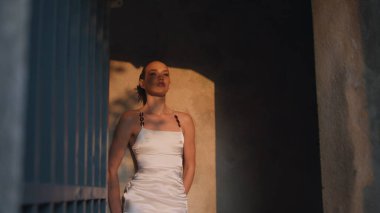 Parlak akşam güneşinde antik şatoya poz veren seksi kız. Ortaçağ binasının girişinde beyaz görkemli elbisesiyle duran şehvetli genç kadın. Göz kamaştırıcı seksi model. Kameranın keyfini çıkar..