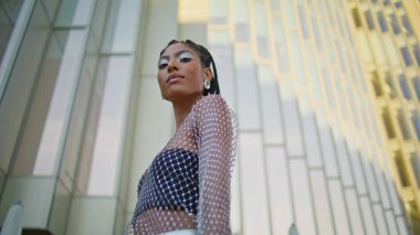 Kendine güveni olan bir kadın yalnız başına şehre yaklaşırken rastlantıya dokunuyor. Koyu renk saçlı şık bayan modern sokak portresi çeken kameraya benziyor. Yaratıcı makyajcı esmer yaz kasabasının tadını çıkarıyor.