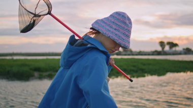 Tatilci kız gün batımında nehir kıyısında dinleniyor. Seyahat eden dişiler yaz kırsalında kelebek ağı tutarlar. Bahar akşamının tadını çıkaran sıradan bir genç kadın. Doğa rahatlama kavramı.