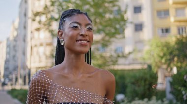 Neşeli esmer kız el sallıyor ve yaz kasabasını kapatıyor. Mutlu Afro-Amerikan kadın selamlaşması Greeny Alley Place 'de. Moda mankeni kız sokakta yürüyor, pozitif ruh hali içinde.