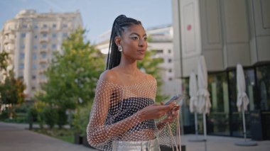 Elinde cep telefonu olan rahat bir bayan caddede yürüyor. Yazın şehir merkezinden geçerken cep telefonu mesajlarını kontrol eden Afrikalı Amerikalı mutlu kadın. Son moda makyaj bildirisine sahip neşeli modacı.