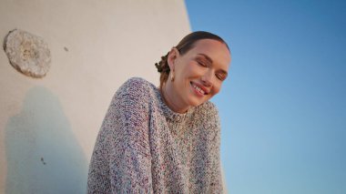 Yakın çekimde mutlu poz akşamları. Sakin sakin kız kırsal alanda hafta sonunun tadını çıkarıyor. Eski kasaba caddesinde kameraya bakan neşeli ve çekici bir kadın. Tasasız gezgin konsepti.