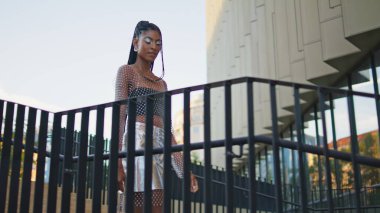 Modern bina şehrinde merdivenlerden inen şık bir model. Dreadlocks çekici Afrikalı Amerikalı kadın merdivenlerde yalnız başına sakin bir şekilde dolaşmaktan hoşlanıyor. Aktif modaya uygun esmer aşağıya inip şehri keşfediyor.
