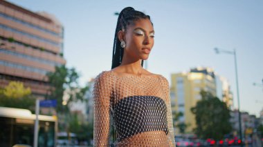 Güneşli cadde kapanışında moda esmer model poz veriyor. Muhteşem stil sahibi bayan yaz havasının tadını çıkarıyor. Şehir fotoğraflarına bakıyor. Moda kadını trafik yolunda tek başına duruyor.