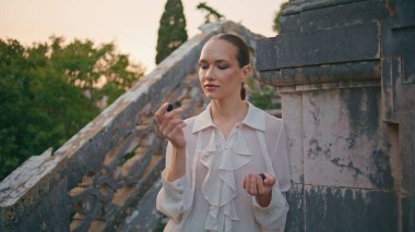 Dışarıdaki eski bina merdivenlerinde böğürtlen kokusundan hoşlanan romantik bir kadın. Rahatlamış çekici kız parmaklarda aromatik vitamin böğürtlenini kokluyor. Sakin model bir avuç organik böğürtlen.