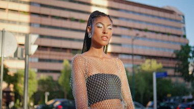 Dreadlocks esmer, sokak resmine poz veriyor. Şehvetli afro örgü ören, modaya uygun giyinmiş bir kadın kameraya yakından bakıyor. Kozmik stil kızı yaz havasının keyfini çıkarıyor.