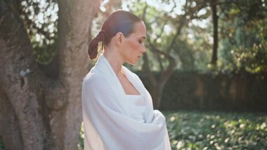 Kız, yeşil geniş ağaçlara bakarak doğayı seyretmekten zevk alıyor. Güneş parkında dinlenen beyaz atkıya sarılmış çekici genç bir kadın. Hayalperest yalnız kadın Bahçe güzelliğini düşünüyor.