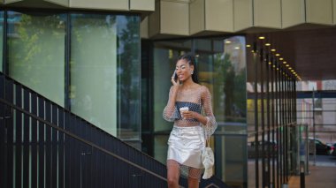 Yürüyen kadın, elinde kahve olan hücreyi arıyor. Mutlu Afro-Amerikan dedikoducu arkadaşı yaz yürüyüşünde iyi haberleri paylaşıyor. Gülümseyen siyah saçlı moda düşkünü, konuşan cep telefonlu.