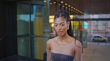 Alış veriş merkezinin arka plan portresinde yürüyen Afro-Amerikan model görünümlü kamera. Yazın sokak kapanışında yaratıcı esmer poz veriyor. Saçları örgülü moda bir kadın güneşli şehir merkezinde tek başına dolaşıyor.