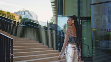 Şık esmer yalnız basamakları çıkıyor. Afrika kökenli Amerikalı turist kız şehir merkezinde yaz tatilinin tadını çıkarıyor. Saç örgülü modacı romantik bir randevuya giden yolda yürüyor.