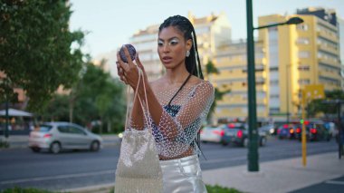 Şehir Bulvarı 'nda makyaj aynası görünümlü şık bir model. Afrikalı Amerikalı moda kadını yürüyüşe hazırlanıyor. Yaz akşamı sokağına tek başına bakıyor. Moda insan yaşam tarzı konsepti