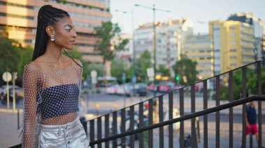 Yaratıcı kız akşam vakti merdivenlerden yukarı çıkıyor. Kendine güvenen Afro-Amerikan kadın merdivene çıkıyor. Güzel esmer kadın modern kasabada merdivenleri hareket ettiriyor. Hafta sonları aktif kasaba hayatı 