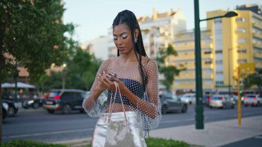 Dreadlocks kızı trafik yolunda aynayı çantasından çıkartıyor. Kahverengi tenli trend bayan makyajını kontrol ediyor. Şehir Bulvarı 'nda eğleniyor. Modern esmer, bekleyen arkadaş akşam bulvarında duruyor.