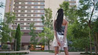 Modern esmer, çağdaş komşuluk görüşü sergiliyor. Afro-amerikan model kamerayı düz portreye çeviriyor. Siyah saçlı kadın şık giyiniyor. Yaz yürüyüşünün tadını çıkarıyor.