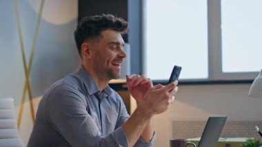 Şirketin CEO 'su internette gezinip cep telefonundan komik mesajlar alıyor. Masada oturmuş akıllı telefon mesajı okuyan mutlu bir işadamı. Pozitif adam iş yerinde eğleniyor.