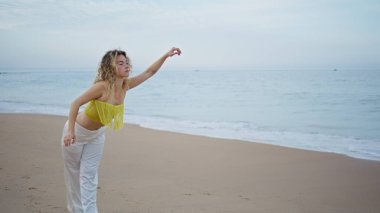 Dans eden güzel kadın kumsalda sakin bir yaz akşamının tadını çıkar. Modern sanatçı, sadece ıslak deniz kıyısına şehvetle ayak basıyor. Modern stilde çalışan profesyonel kadın koreograf..