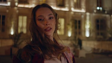 Sokak mankeni gülümseyen bir kameraya dönüşüyor. Güzel kasabanın önünde poz veren, uzun saçlı, tasasız, mutlu bir kadın. Rahat moda kızı yalnız başına akşam gezintisinin tadını çıkar..