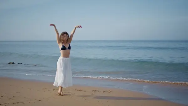 Dancer woman raising hands walking beautiful summer beach. Gorgeous performer moving gracefully stepping on wet sand. Seductive girl dancing looking picturesque seascape. Modern choreography concept.