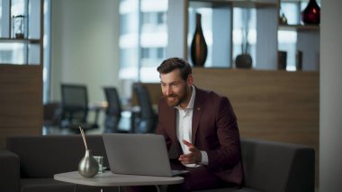 Ofis binasında duygusal jestler yapan coşkulu bir adam. Basarinin heyecanini ifade eden tatmin edici bir CEO. Başarılı patron, video çağrısında zaferi kutlayan iyi haberleri paylaşıyor. Zafer konsepti 