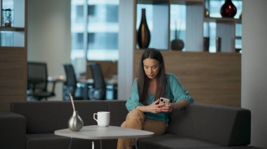 Depresyonda olan bir kadın cep telefonuyla iş yerinde koltuğu dinlendiriyor. Dalgın üzgün bayan dinlenme koltuğu lüks bir yerde kırılmış hissediyor. Cep telefonu tutan üzgün iş kadını sorun yaşıyor