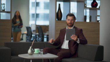 Büyük ve rahat kabinede video konferansından bahseden mutlu girişimci iş adamı. Gülümseyen profesyonel sakallı emlakçı ofisin içini arıyor. Modern şirket dijital çalışma konsepti.
