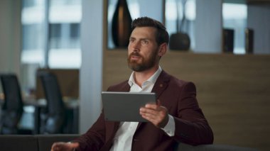 Sinir bozucu yönetici, ofiste el kol hareketi yaparak tablet bilgisayardan bahsediyor. Ciddi profesyonel bir avukatın şirket kabinesinde önemli bir video görüşmesi var. Dijital konferans çalışma konsepti