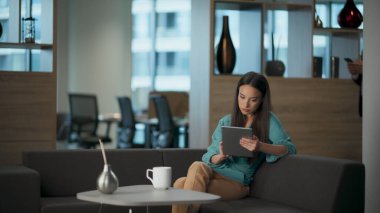 Açık alanda tablet e-posta okuyan ciddi bir kadın. Şirket molasında kendine güvenen girişimci bilgisayarlı mesajları kontrol ediyor. Lüks iş birliğinde modern dijital cihaz yazan odaklanmış yönetmen bayan.