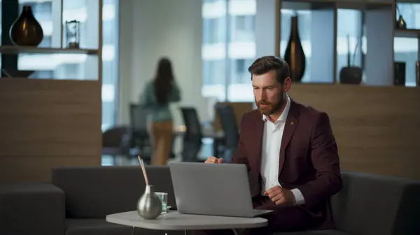 Aggressive guy watching computer at coworking room. Angry person getting unexpected news working in office. Bearded businessman emotionally gesturing hands feeling furious. Business problems concept