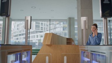 Çalışan şirket ofisinde otomatik güvenlik turnikesi istasyonu açıyor. İş kadını, iş merkezinin elektronik kapı girişinden geçiyor. Telefonu arıyor. Gülümseyen kadın kimlik kartı kullanıyor..