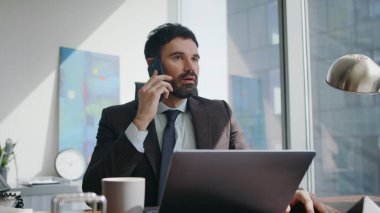 Hayal kırıklığına uğramış işçi telefon konuşmaları, modern şirket ofisinde otururken kötü haberler duymak. Hüsrana uğramış sakallı yönetici, masadaki telefon görüşmesiyle laptopun arasında kalmış. Sinirli CEO konuşan cep telefonunu kapat..