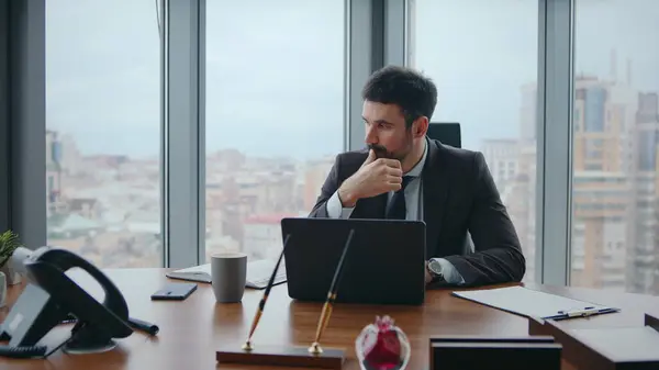 Busy office worker sitting luxury workplace thinking at company crisis close up. Thoughtful businessman worried business perspectives working at laptop. Bearded manager solving corporate problems.